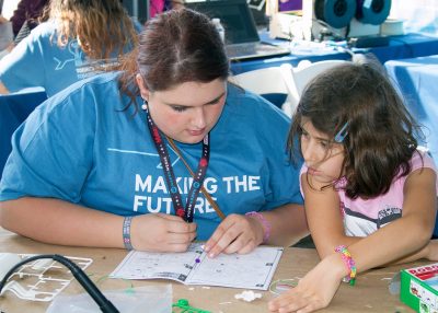 Teen leader helps a young maker to create a solar powered boat.
